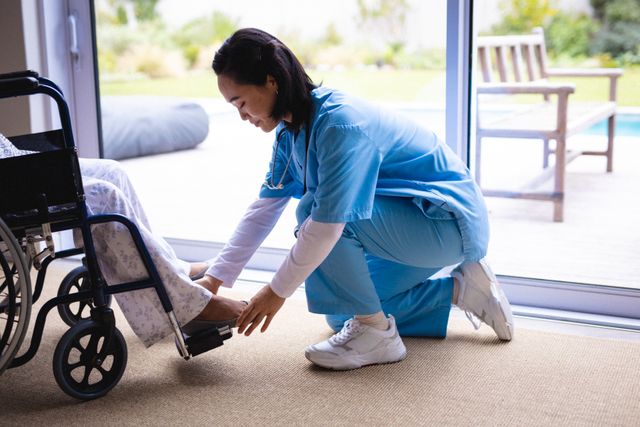 Asian nurse providing assistance to a senior patient in a wheelchair, ideal for illustrating healthcare, elderly care, and medical support services. Useful for websites, brochures, and articles related to nursing homes, rehabilitation centers, and home care services.
