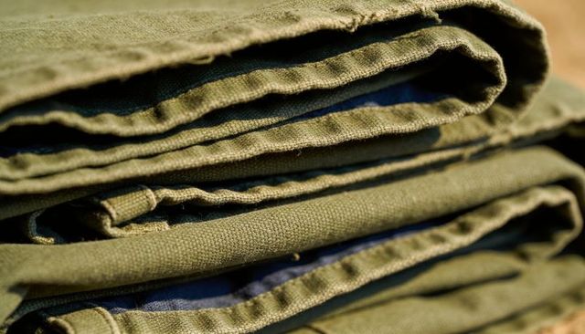Folded olive canvas closeup showing frayed hems and blue lining texture