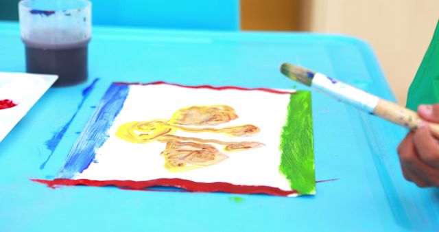 Cute little boy painting at table in classroom in playschool