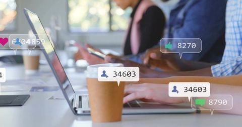 Typing on laptop in modern coworking office with social media overlays and teamwork