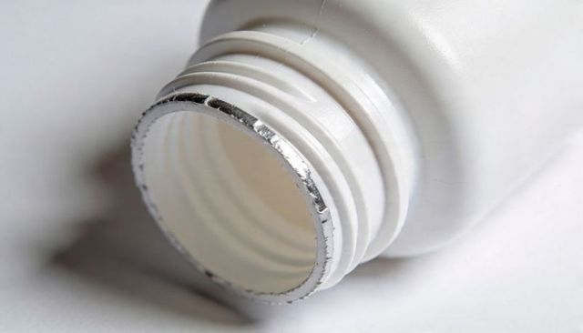 Close-up of White Plastic Bottle Neck with Torn Foil Seal and Visible Screw Threads