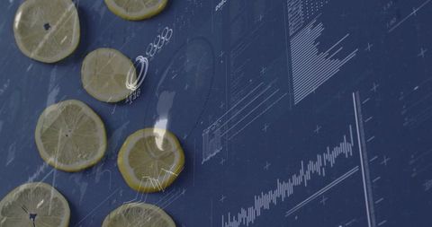 Thin lemon slices lying on navy surface overlaying white digital charts and data graphics