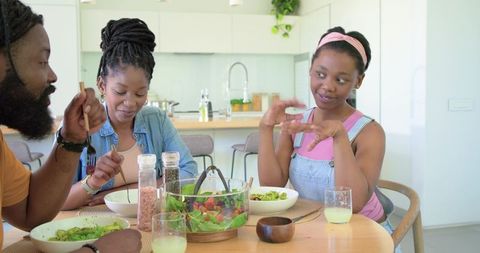 African american family sharing healthy salad at sunlit modern kitchen table