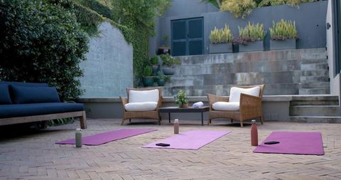 Outdoor yoga class setup with three purple mats on herringbone brick courtyard for wellness retreats