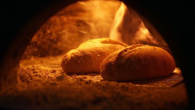 Artisan loaves baking in rustic wood-fired brick oven