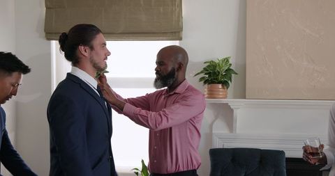 Groom preparing with best man adjusting tie before wedding