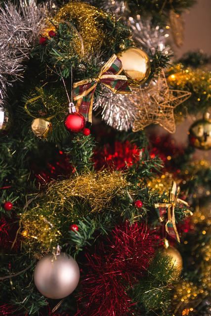 This close-up image of a Christmas tree adorned with various festive decorations, including baubles, tinsel, and ribbons, is perfect for holiday-themed projects. It can be used in advertisements, greeting cards, social media posts, and blog articles to evoke the spirit of Christmas and the holiday season.