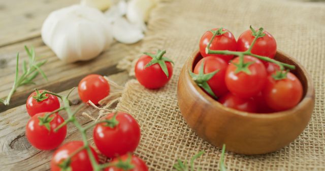 Image of fresh cherry tomatoes in bowl and garlic on rustic cloth over wooden background - Download Free Stock Photos Pikwizard.com