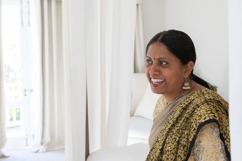 Smiling Indian Woman in Gold Sari Relaxing Indoors