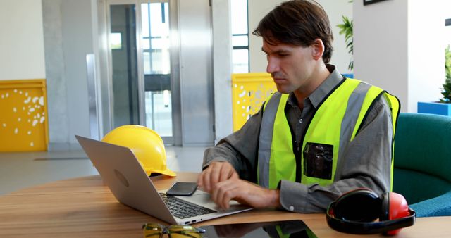 Engineer in Office Analyzing Construction Plans on Laptop - Download Free Stock Images Pikwizard.com