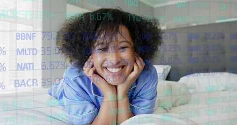 Smiling woman lying on bed wearing light-blue satin pajamas with stock ticker overlay