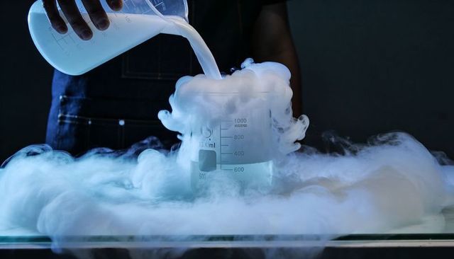 Pouring liquid into 1000ml beaker producing dense fog and vapor for lab demonstration