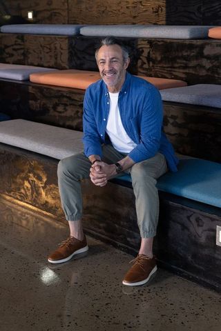 Confident middle-aged man sitting on modern tiered bench wearing blue overshirt