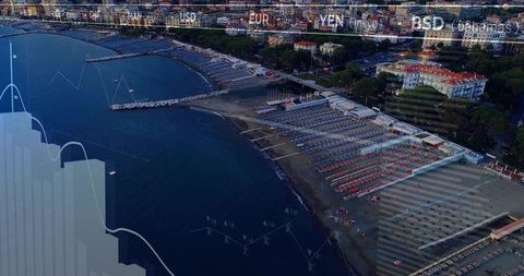 Overlooking coastal resort with striped beach cabins, sunbeds, jetty and financial overlay