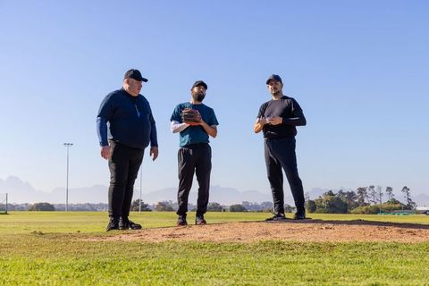 Baseball coaches coaching players on mound blowing whistle while tracing pitch trajectory