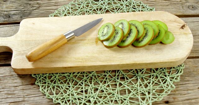 Freshly sliced kiwifruit arranged on a wooden cutting board with a knife next to them. Perfect for use in healthy food blogs, recipes, kitchen tutorials, or organic product promotions. Highlights the simplicity and freshness of nature-inspired food. Excellent for illustrating fresh fruit preparation in cookbooks or food magazines.