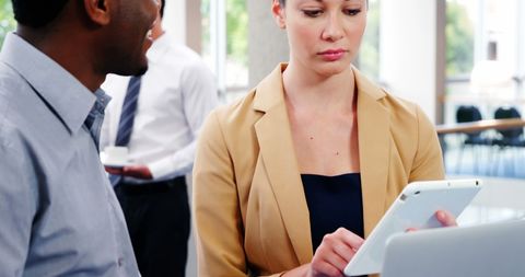 Professionals Collaborating on Digital Tablet in Modern Office