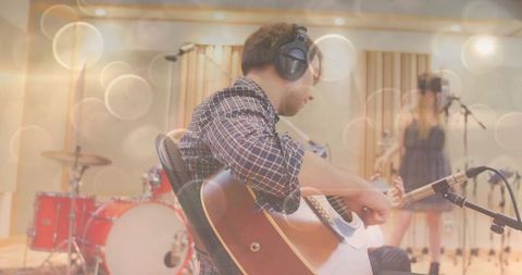 Musician recording acoustic guitar in professional studio