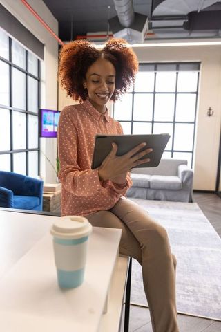Smiling Professional Woman Engaged with Digital Tablet in Office
