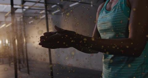 Clapping hands applying chalk before workout in industrial gym with backlight and dust