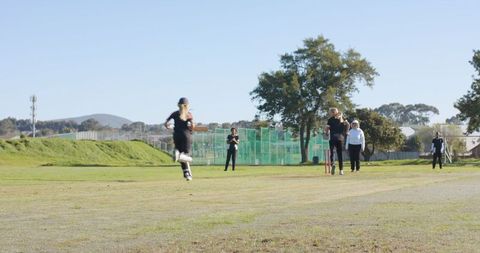Diverse Women Engaging in Cricket Match on Sunny Field