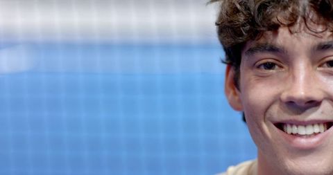 Man smiling on outdoor blue tennis court