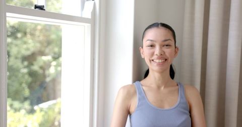 Cheerful Young Woman Smiling by Sunlit Window