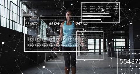 Woman lifting dumbbell with augmented reality fitness data overlays in industrial warehouse gym