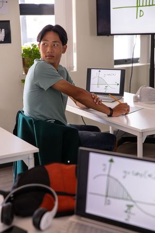 Teenage asian student studying with laptop graph and notebook for math learning in modern classroom
