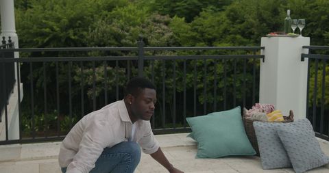 Man Relaxing on Outdoor Patio with Snacks and Wine Glasses