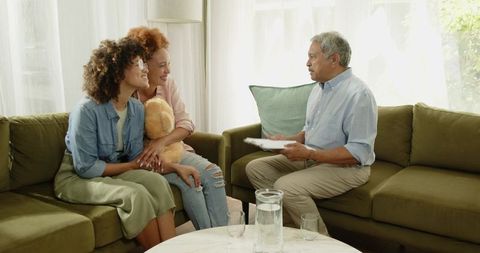 Intergenerational Family Consulting with Senior Man on Green Sofa Holding Teddy Bear