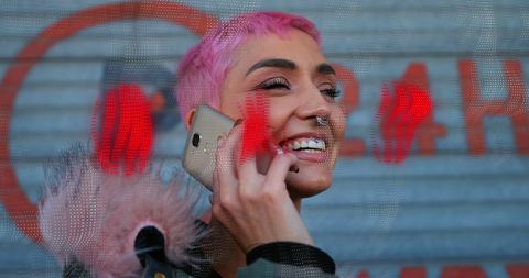 Young Woman with Pink Hair Talking on Smartphone in Urban Area