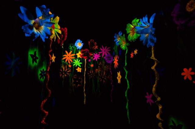 Fluorescent flowers glowing brightly in a dark room creating a surreal and psychedelic atmosphere. Ideal for use in advertisements for clubs, parties, and events. Captures the beauty of illuminated art installations perfect for creative marketing campaigns or backgrounds.
