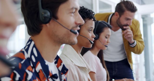 Diverse office team at work in a call center. Colleagues with headsets engage with clients, ensuring customer service excellence.