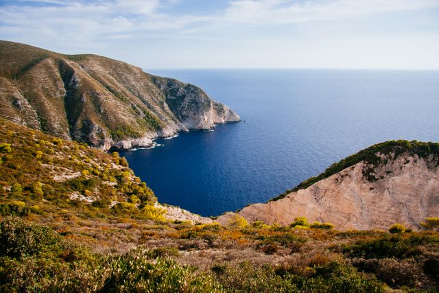 This depicts a remote bay surrounded by rugged ocean cliffs and clear, blue water. Ideal for travel blogs, nature articles, posters, or backgrounds for presentations emphasizing natural beauty and adventure.