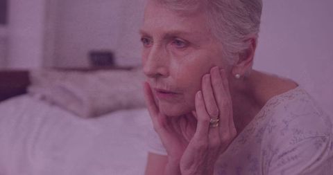 Pensive Elderly Woman Contemplating in Dimly Lit Room