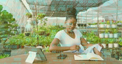 Urban greenhouse worker documenting plants using tablet, notebook for sustainable growth