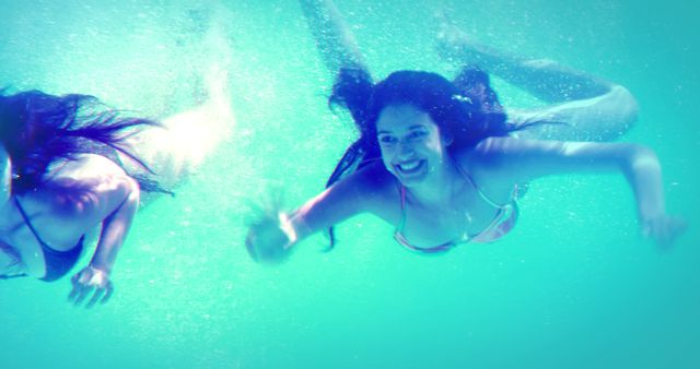 Happy friends in bikinis diving into swimming pool on her holidays