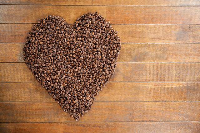 Heart shaped coffee beans on wooden table, perfect for illustrating love for coffee. Ideal for use in coffee shop promotions, cafe menus, coffee-related blogs, and social media posts celebrating coffee culture.