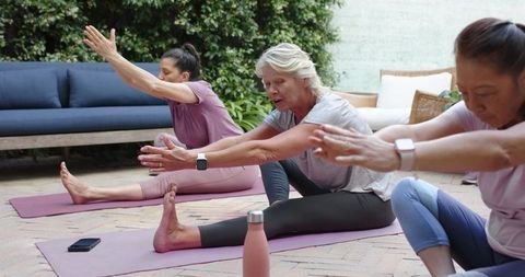 Multigenerational women stretching on patio yoga mats for active aging and wellness