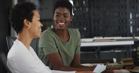 Two Businesswomen Collaborating and Smiling in Modern Office