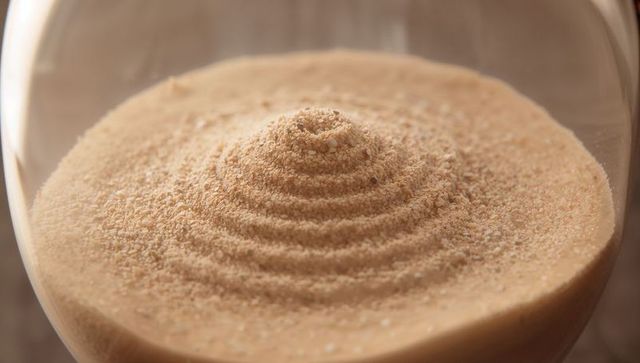 Artistic conical blonde sand forming spiral in glass vessel