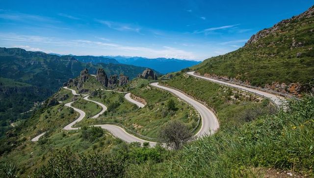Scenic mountain pass road surrounded by rocky landscape and blue sky