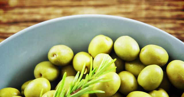 Bowl of Fresh Green Olives with Rosemary on Wooden Table - Download Free Stock Images Pikwizard.com