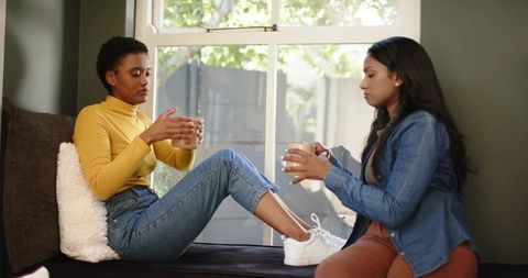 Diverse Friends Chatting in Cozy Home Setting by Window