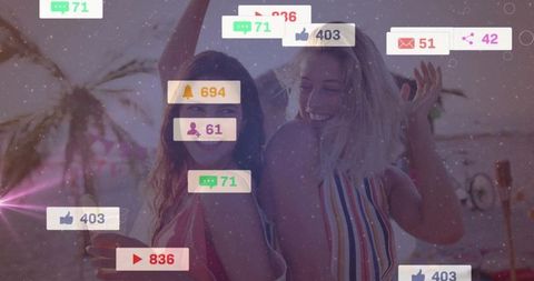 Carefree friends enjoying social media on beach at sunset