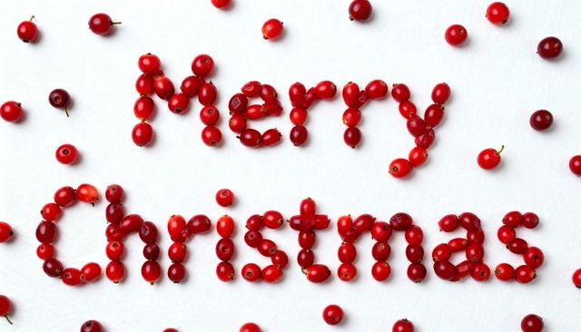 Merry Christmas spelled with red cranberries on white textured background, flatlay, minimal