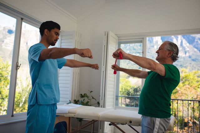This image depicts a physiotherapist assisting a senior man with resistance band exercises in a home setting. Ideal for use in articles, blogs, and websites related to elderly care, home healthcare services, physical therapy, and senior fitness programs. It can also be used in promotional materials for physiotherapy clinics and home care services.