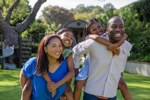 Happy multiethnic family piggybacking in sunny backyard