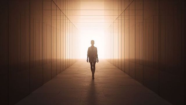 Solitary Woman Walking Toward Bright Light in Glass Corridor with Symmetrical Reflections